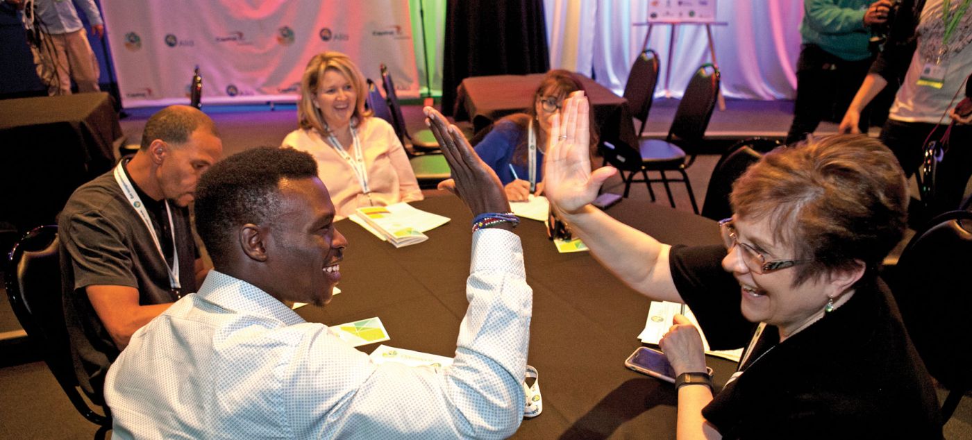 Two participants high-five at the Ten for Ten conference