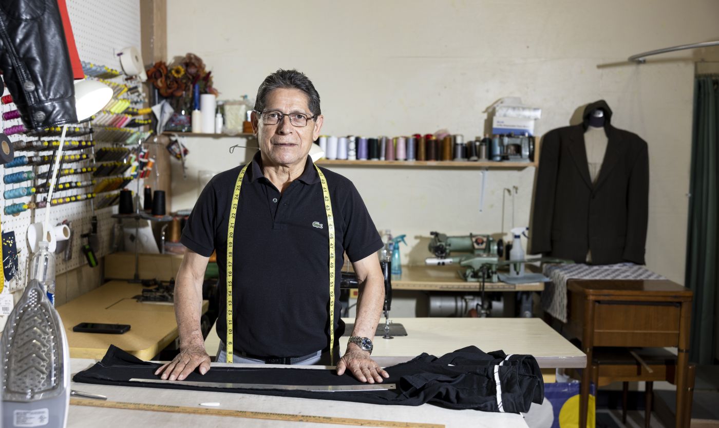 man measures pants on a table in a tailor shop to make alterations