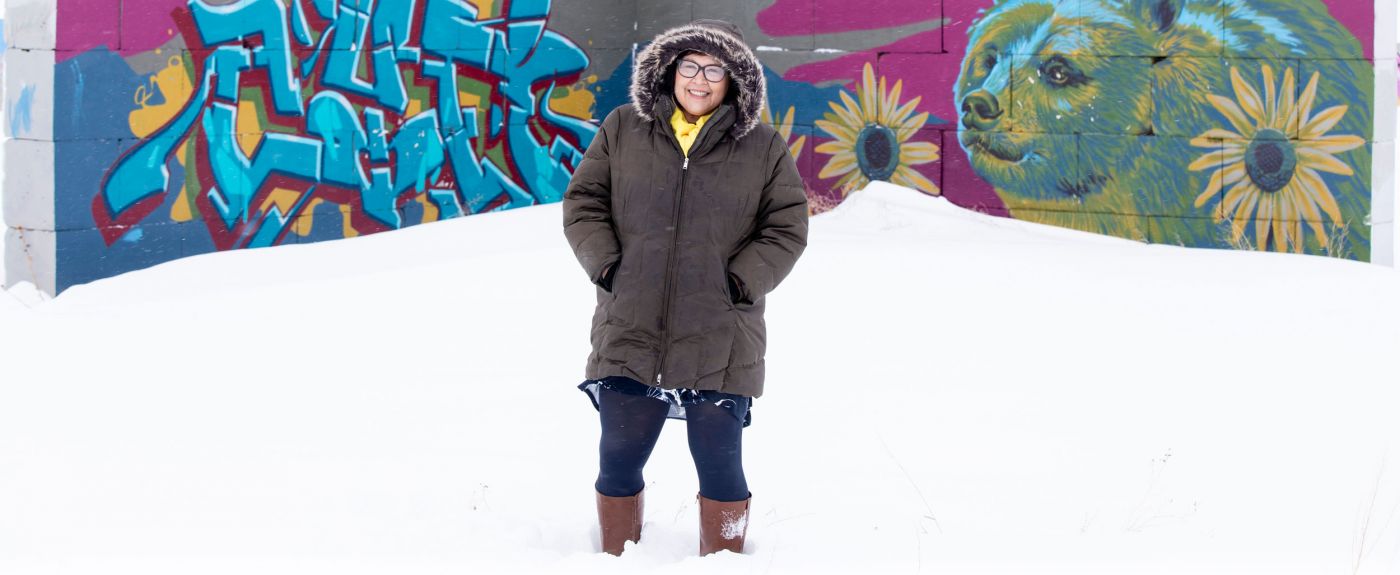 Julie Garreau in the snow and winter coat in front of graffiti art on wall